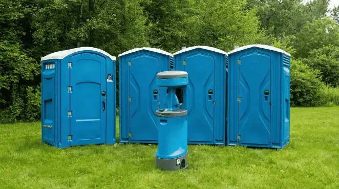 Four blue portable toilets and a matching hand washing station on grass near trees, a common sight at local outdoor events in Minneapolis, MN